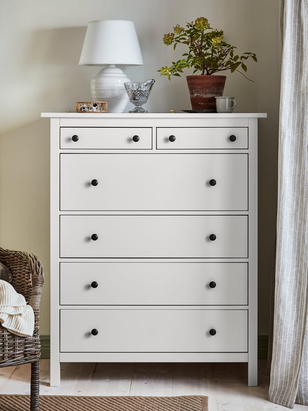 Hög vit HEMNES byrå i hall på ben. 