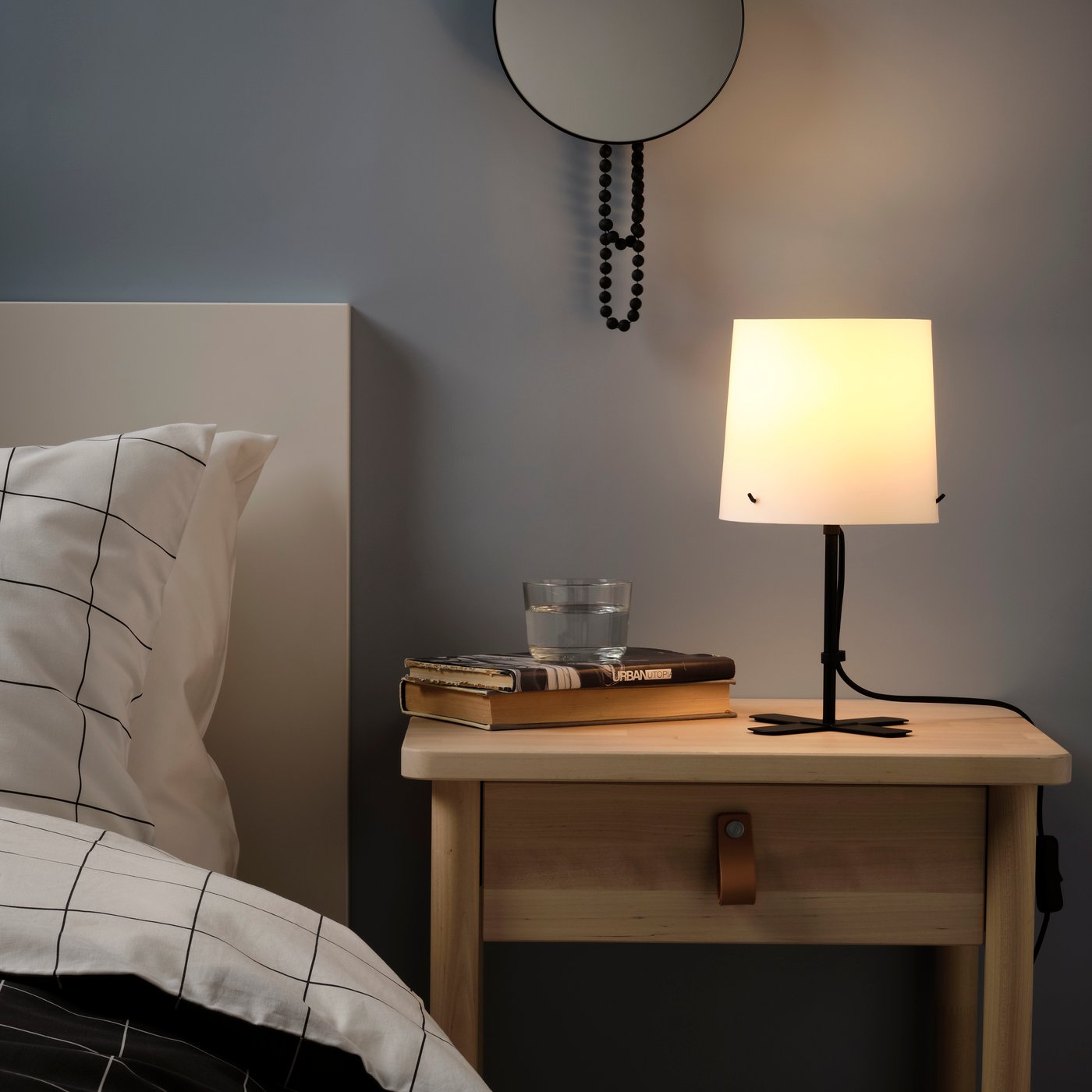 A black/white BARLAST table lamp in the bedroom
