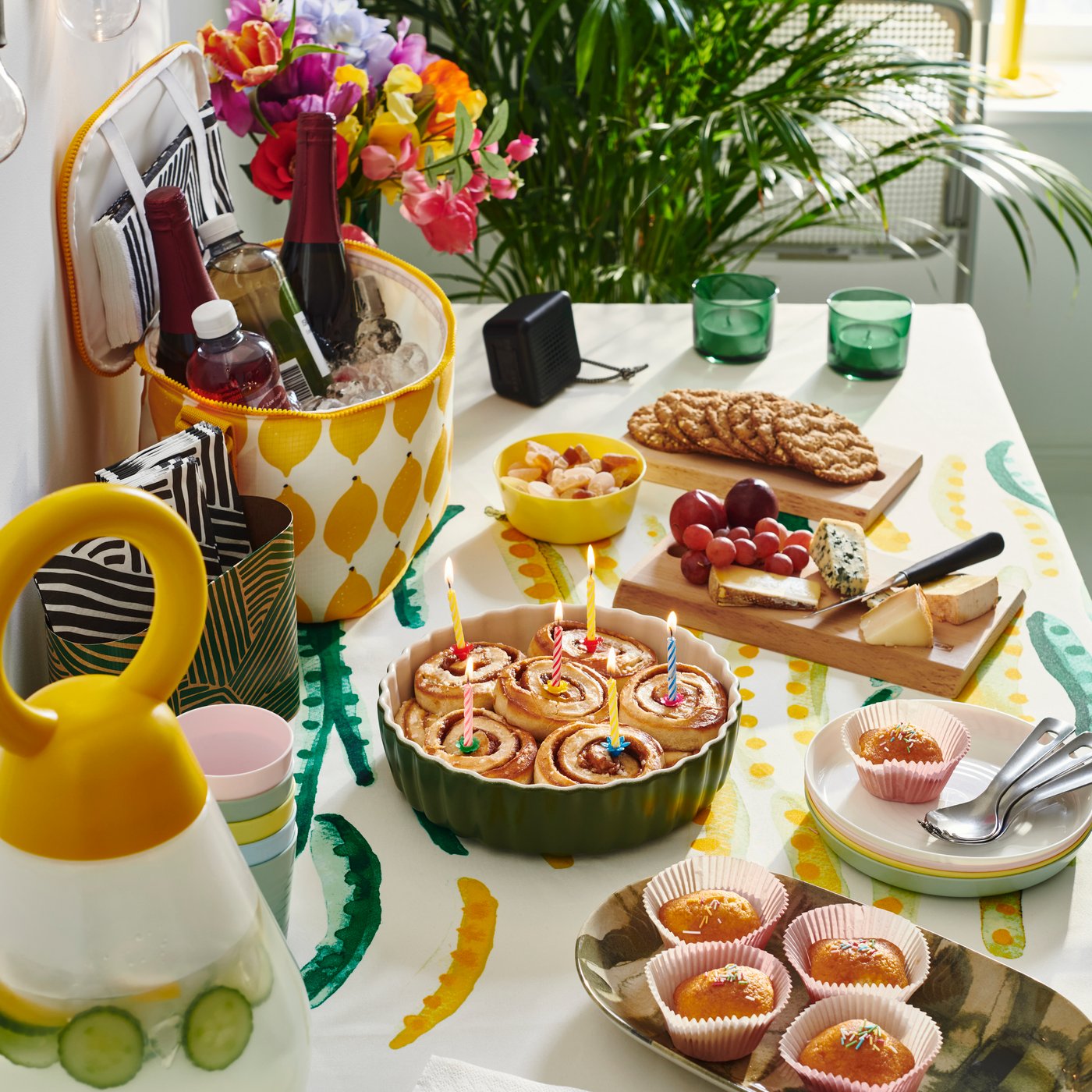 Ett bord är dukat med fika, en färgglad kylväska med dryck i och andra tillbehör till sommarfesten i färgglada kulörer.