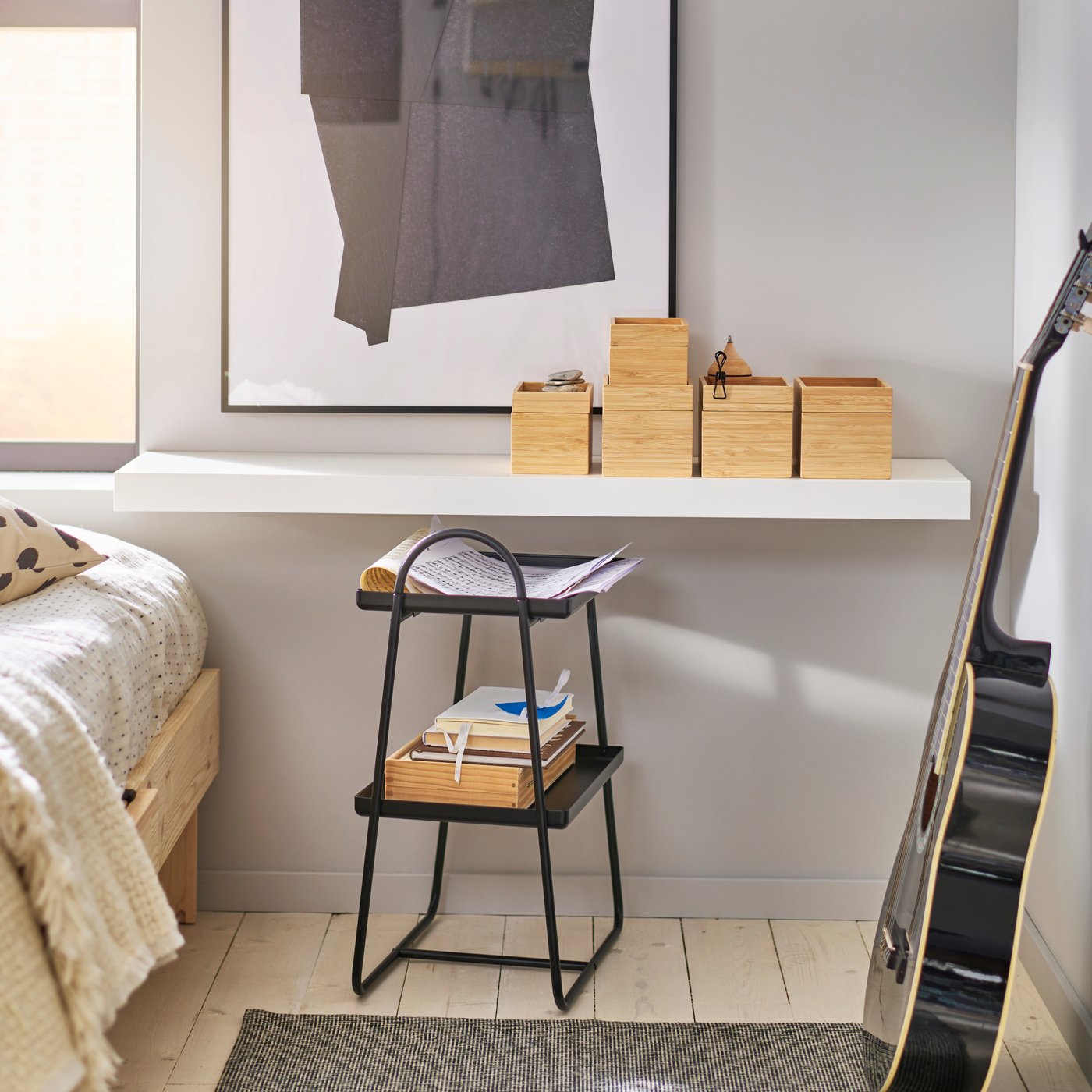 Bedroom with LACK wall bench with wooden boxes on it. HATTÅSEN bedside table/shelving unit and a guitar leaning against the wall.