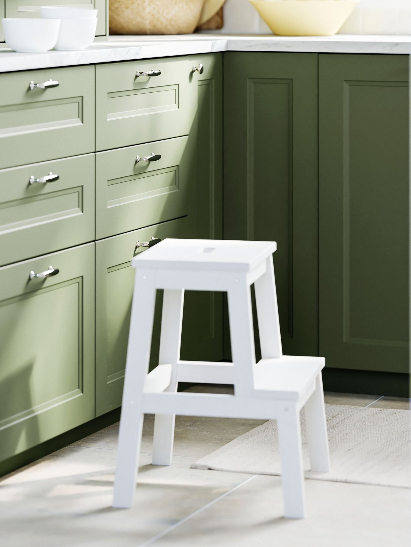 A green AXSTAD kitchen with a white EKBACKEN worktop with a lively marble effect/laminate finish in the kitchen.