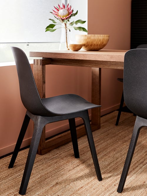 Chaises ODGER anthracite, table garnie de bols et d’une fleur, fenêtre dans le fond.