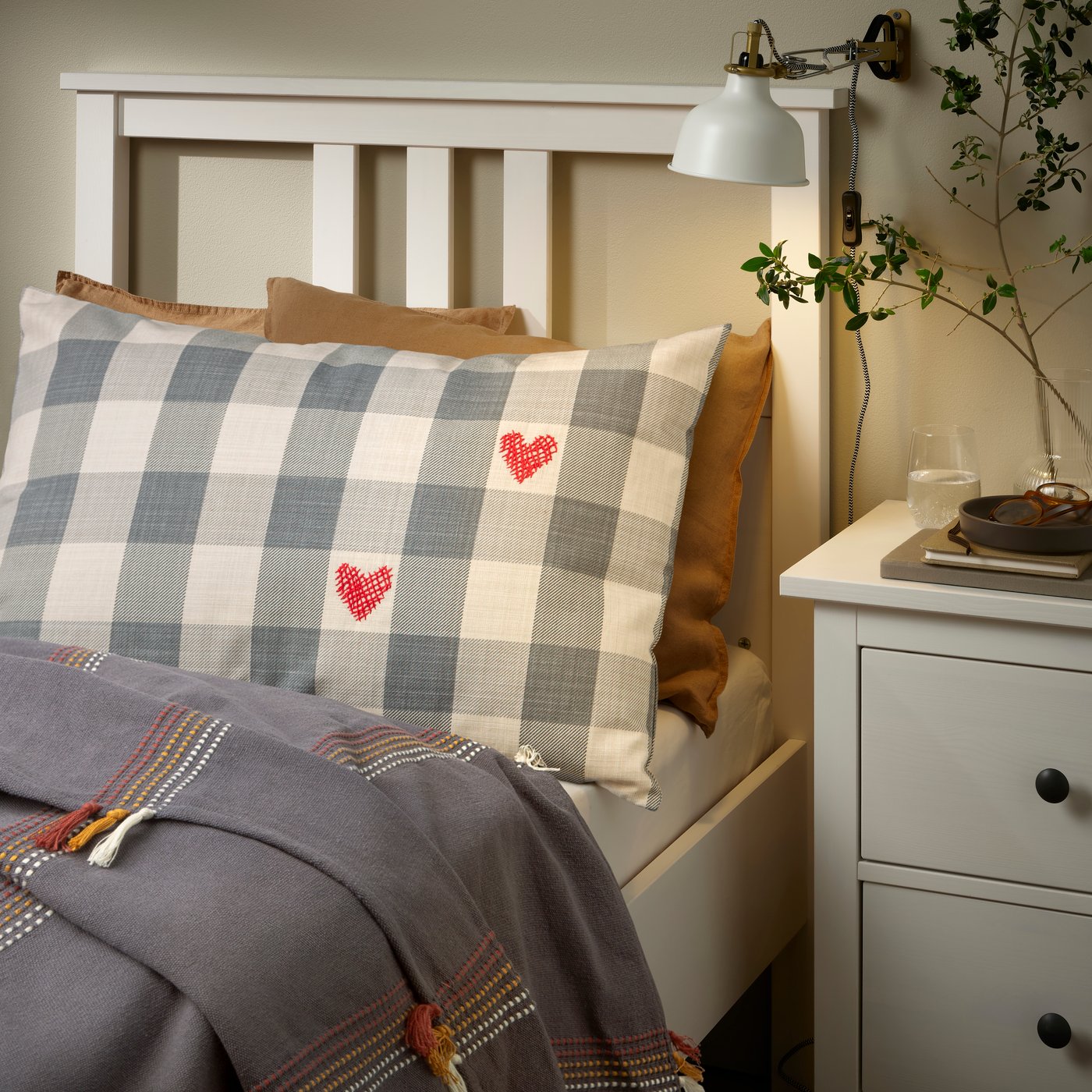 Ein karierter grau/herzroter MÄVINN-Kissenbezug.