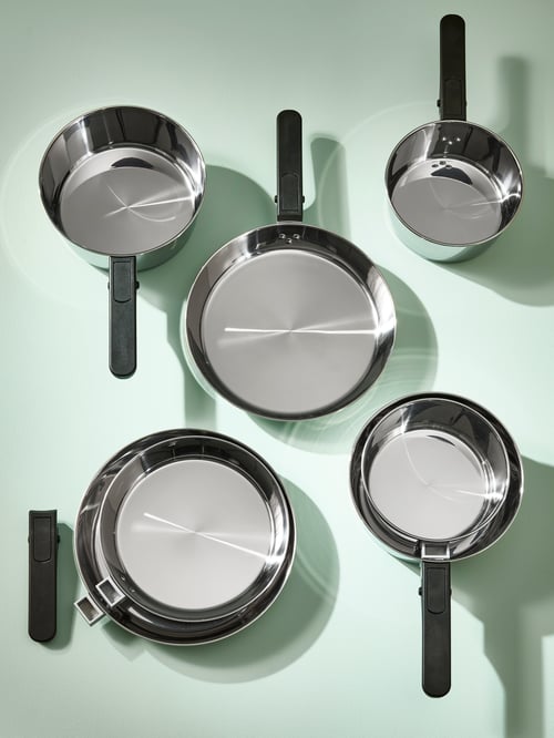 Overhead shot of SLÄTROCKA cookware item such as frying pans and saucepans, all set on a light-green surface.