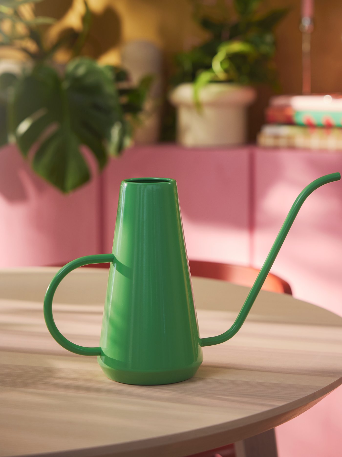 A bright green DOFTRIPS watering can on a round table in a colourful room. The can’s narrow spout is perfect for small shoots.