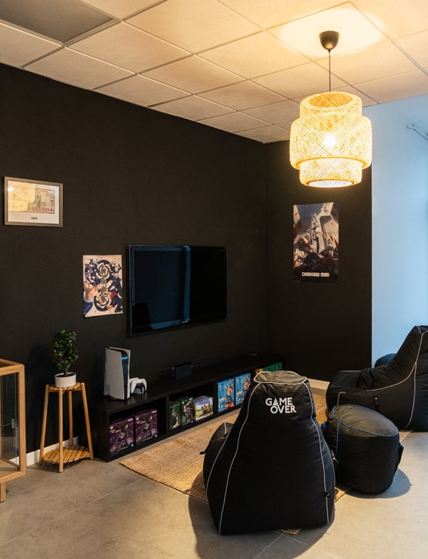 L'angolo dedicato ai videogiochi con due poltrone nere e illuminato da una lampada a sospensione SINNERLIG.
