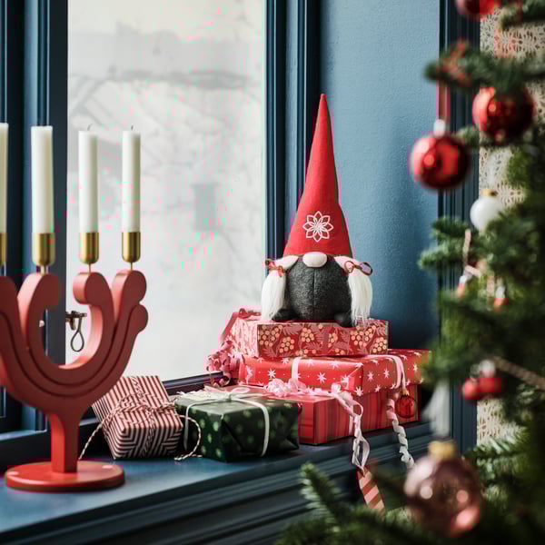 Juldekoration och en julljusstake i ett blått fönster.