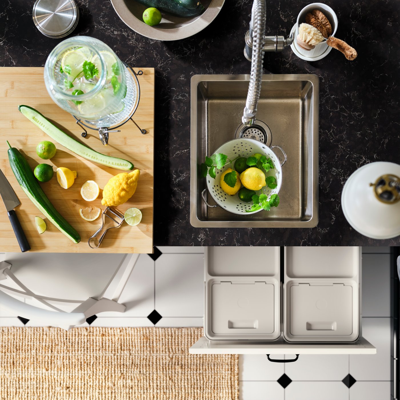 Passoire remplie de citrons et d’herbes aromatiques dans un évier VRESJÖN en acier inoxydable encastré dans un comptoir noir.