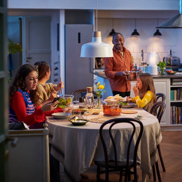 A family is sitting around a dining table with a white/smart STARKVIND air purifier in the background.