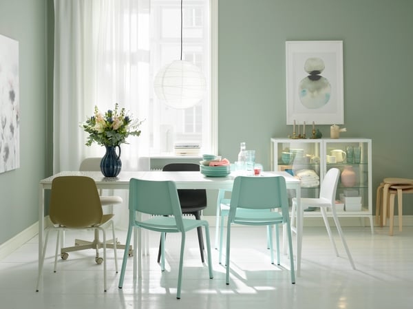 Un comedor con 4 sillas de diferentes colores y materiales.