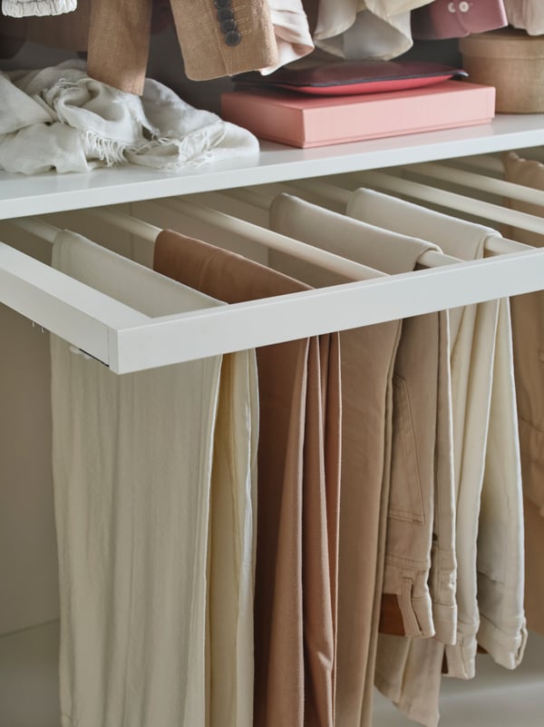 A white KOMPLEMENT pull-out trouser hanger in the bedroom