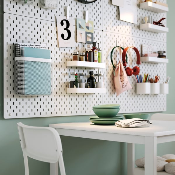 A white VIHALS table surrounded by two chairs, set in a bright kitchen with SKÅDIS pegboards and decor.
