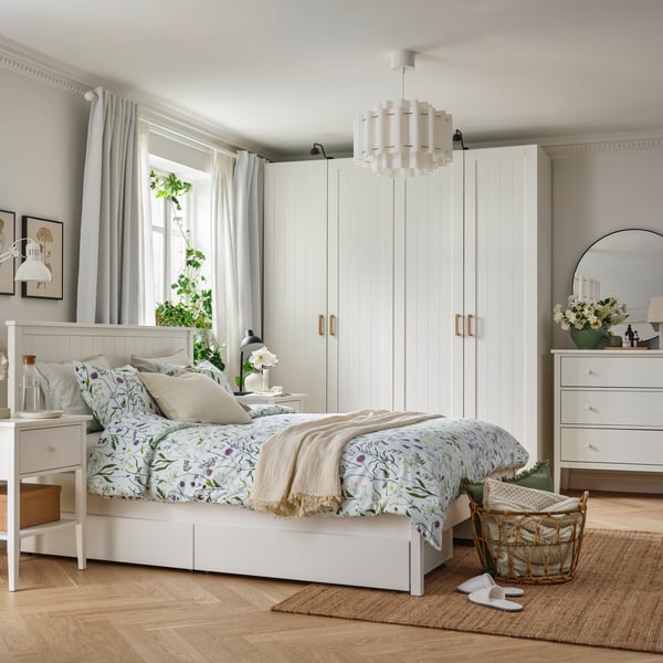 A bedroom featuring a white GULLABERG bed frame with four storage boxes, PAX/GULLABERG wardrobe combination and plants.
