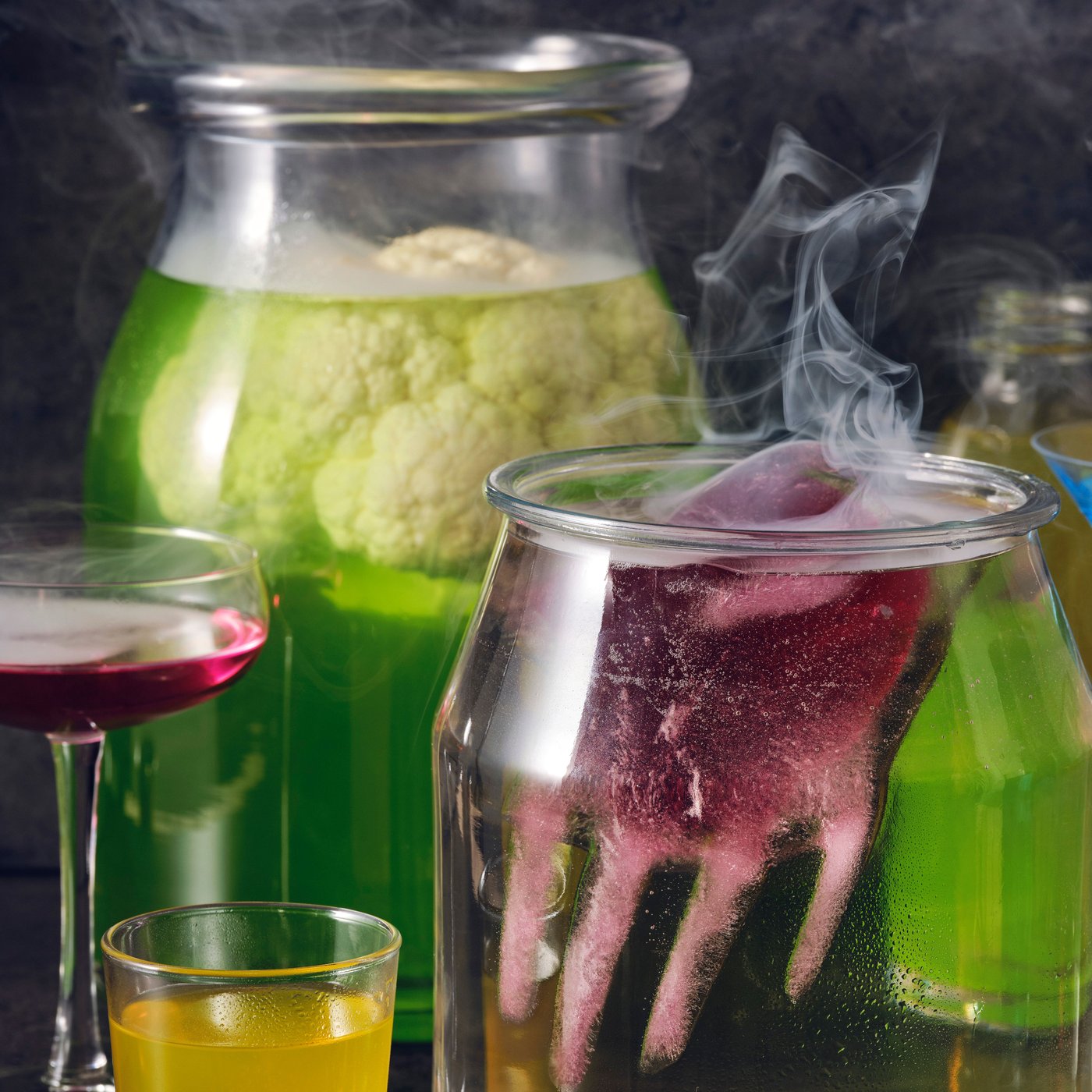 Cocktails in jars and glasses including a spooky punch made with DRYCK FLÄDER elderflower syrup and a red hand floating on top.