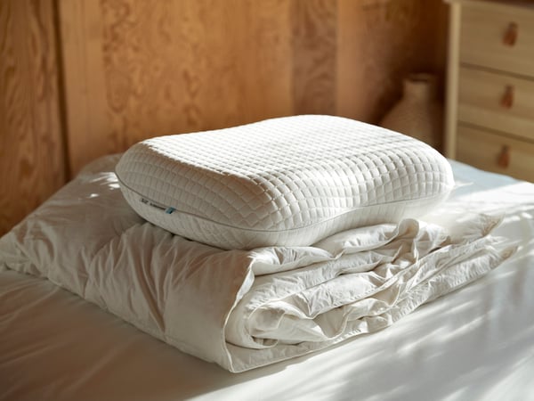 A woman, laying on her stomach, is sleeping deeply on IKEA KLUBBSPORRE ergonomic pillow.