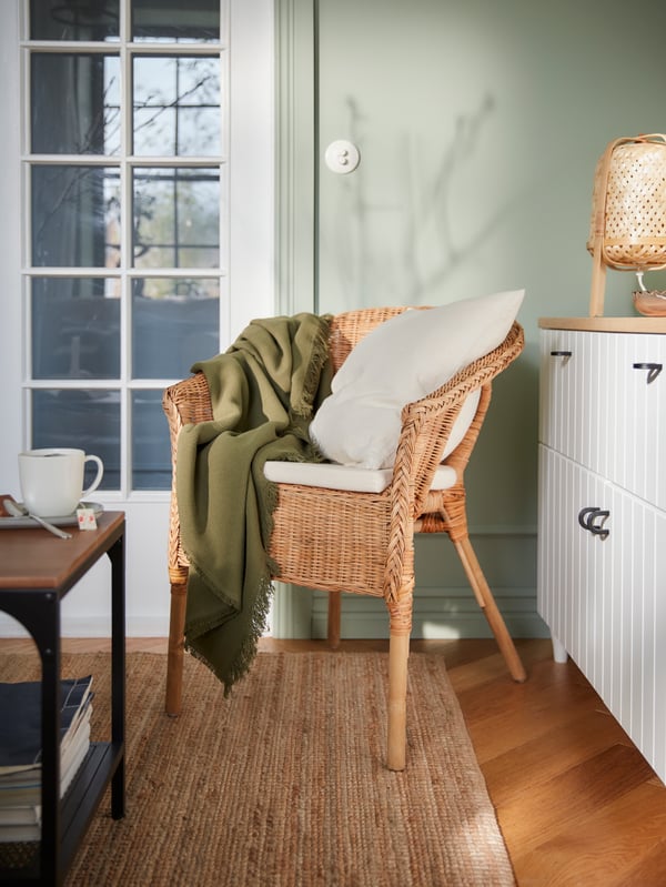 Ein Wohnzimmer mit grafischen Mustern, vornehmlich in Weiß gehalten und u. a. mit einem AGEN Sessel aus Rattan.