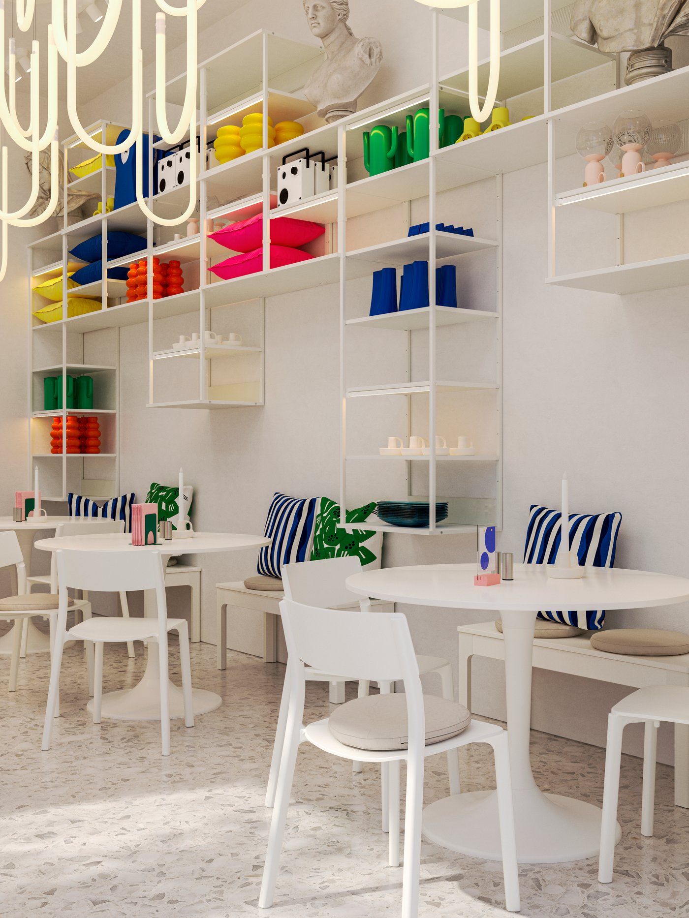 A café with white tables, chairs and wall-mounted PLATSA open shelving units displaying colourful home decoration products.
