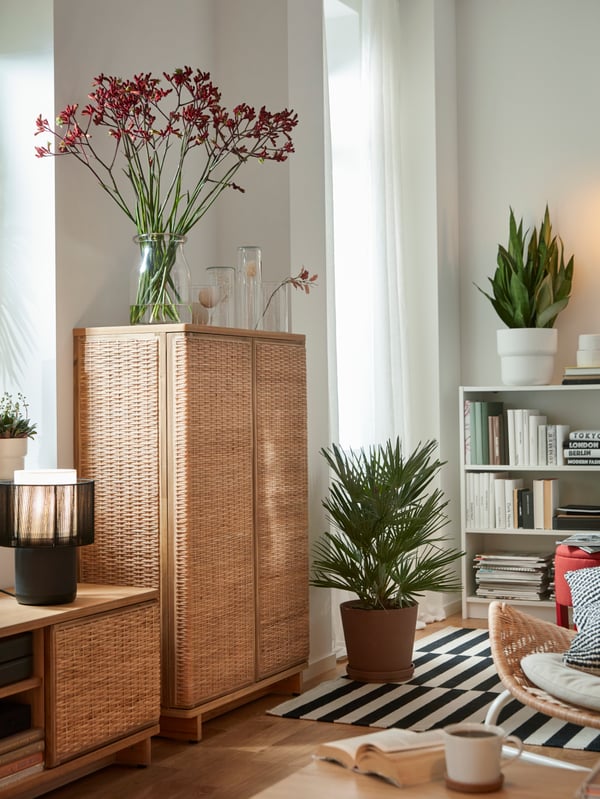 Part of a bright living room with a FRYKSÅS TV bench and cabinet standing side by side, a large flower vase on the latter.