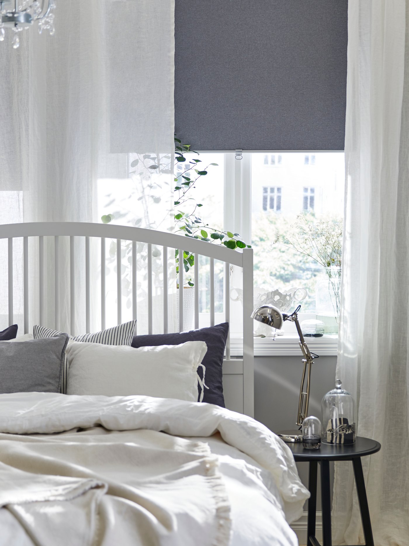 A bedroom with two FYRTUR block-out roller blinds, half-way down, in two windows above some chests of drawers.