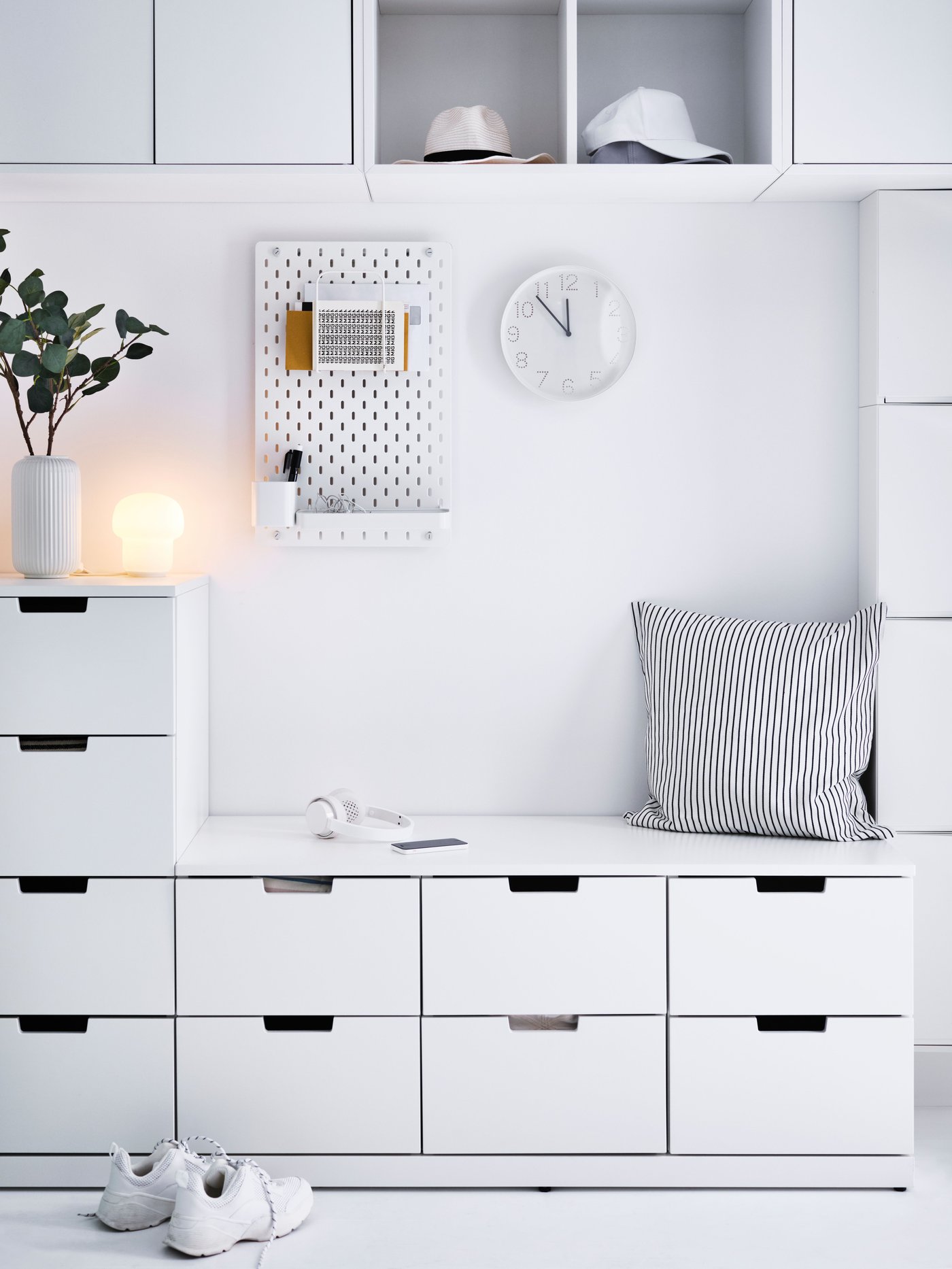 Volledig witte hal waar bijna een hele wand wordt ingenomen door een combinatie van witte NORDLI ladekasten.