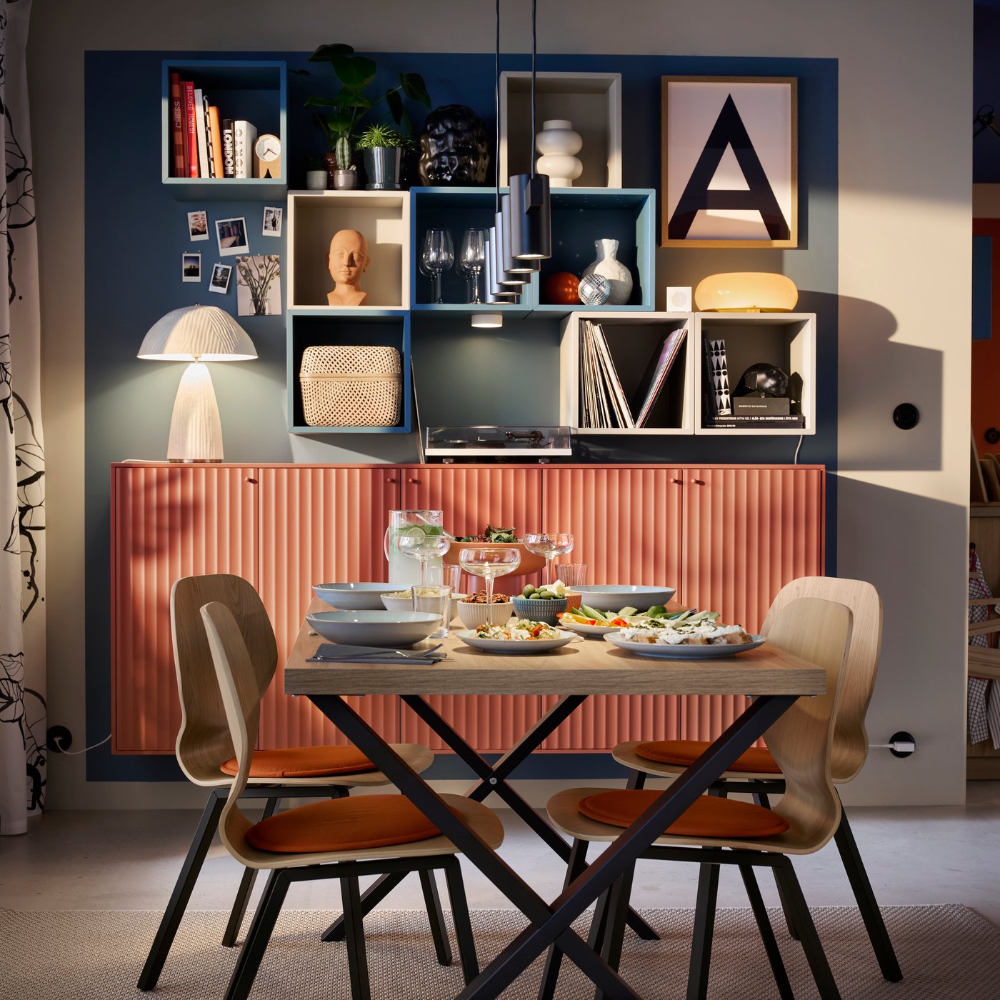 A SKÅLSTA table in oak veneer with black legs has four matching chairs and there’s a storage solution in the background.