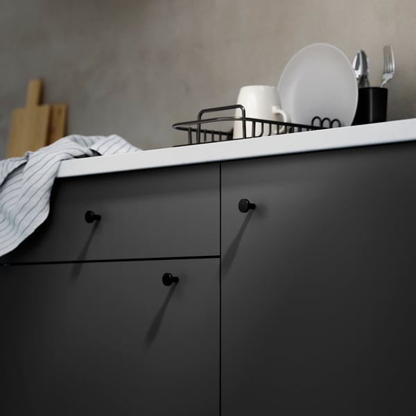 A sleek grey kitchen countertop showcases a minimalist design with dishes, a bowl, and utensils neatly arranged.