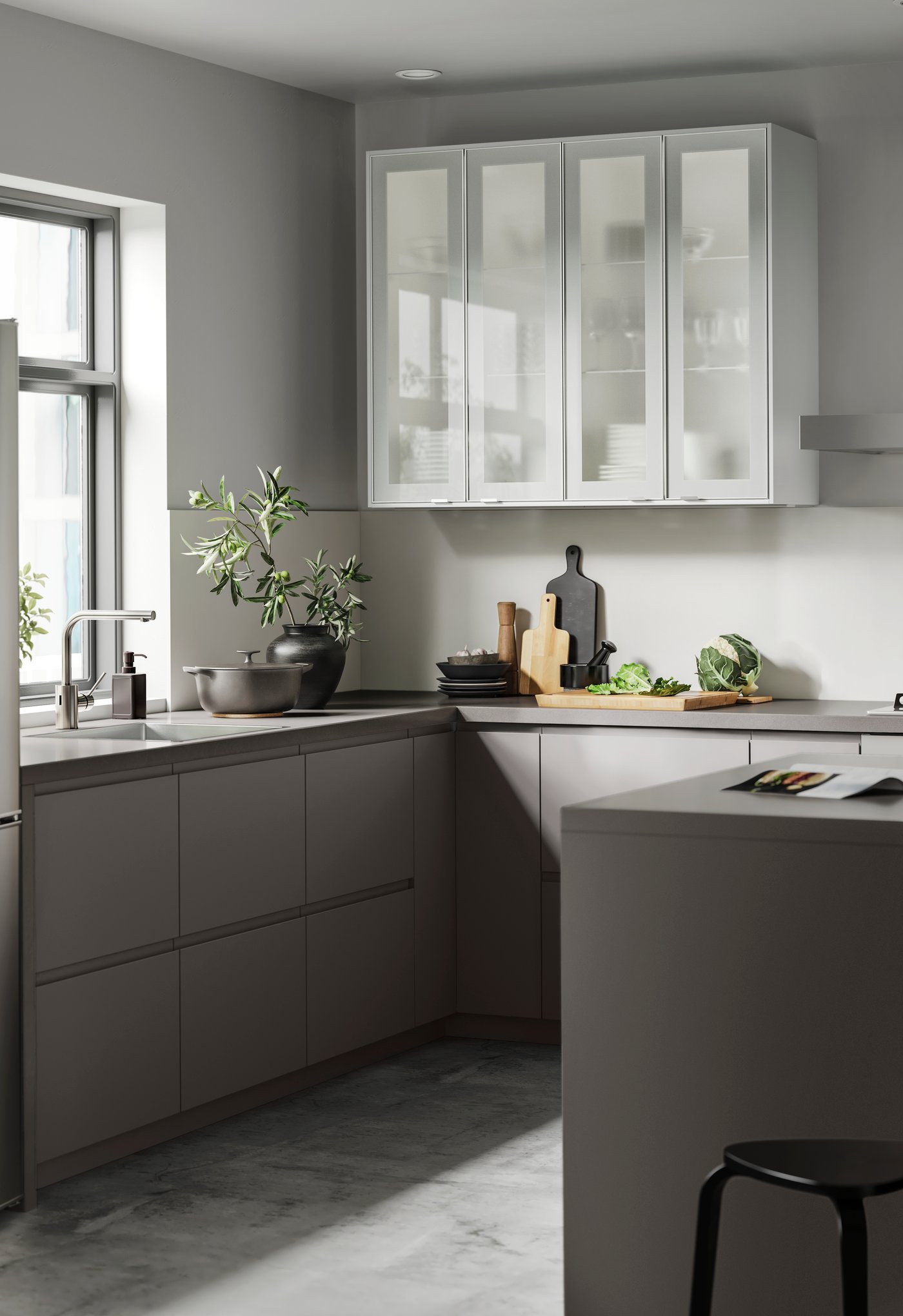 Ett grått hörnkök med vita väggskåp och ett fönster.