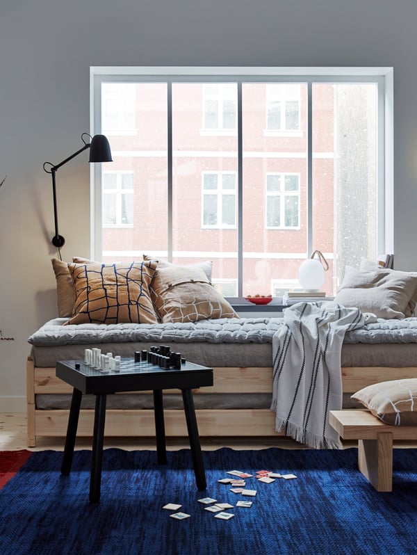 A blue VÄRMER rug, flat-woven in the living room in front of stacked UTÅKER beds.