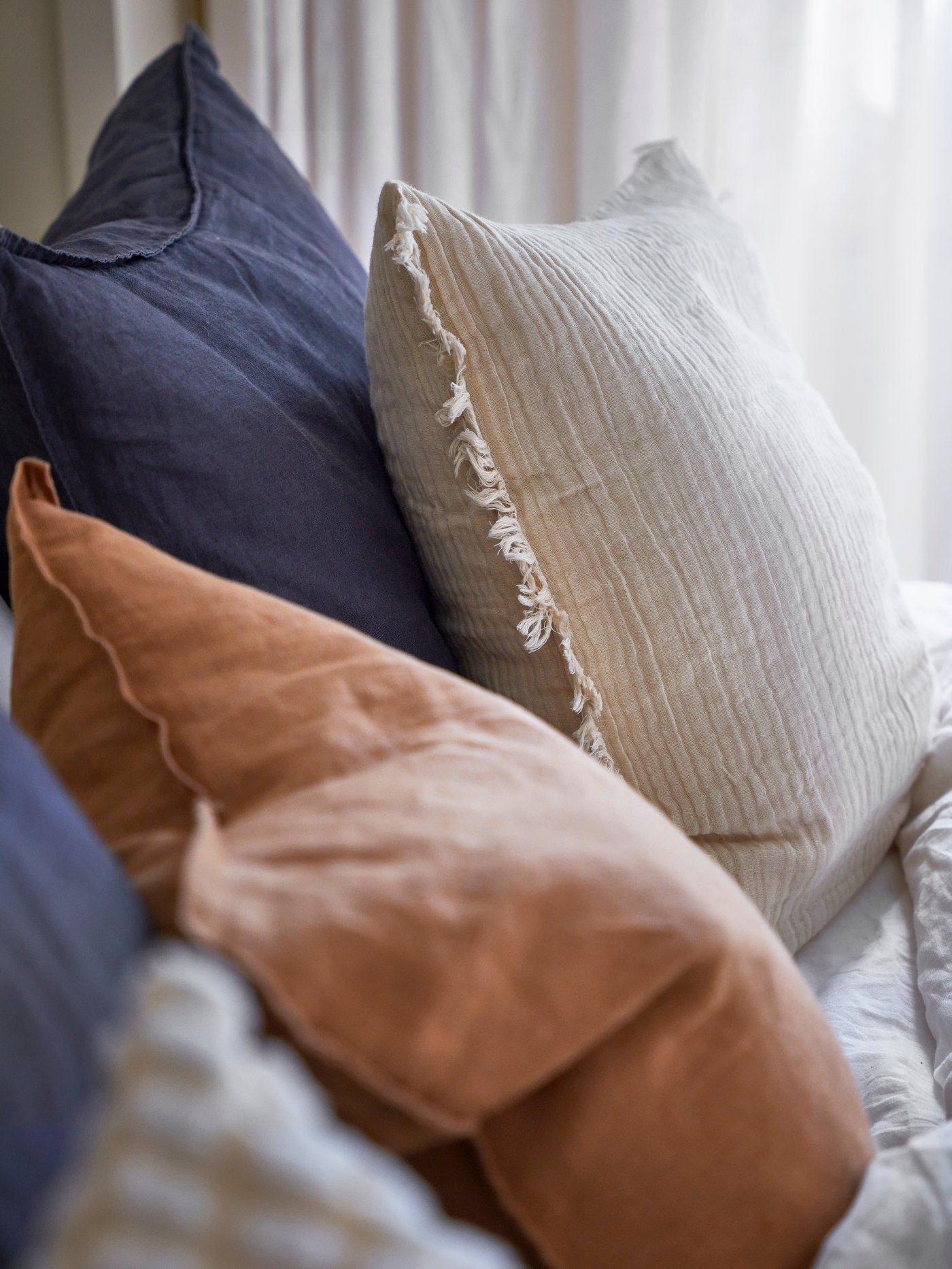 Kuddfodral i linne i beige, mörkgrått och offwhite.