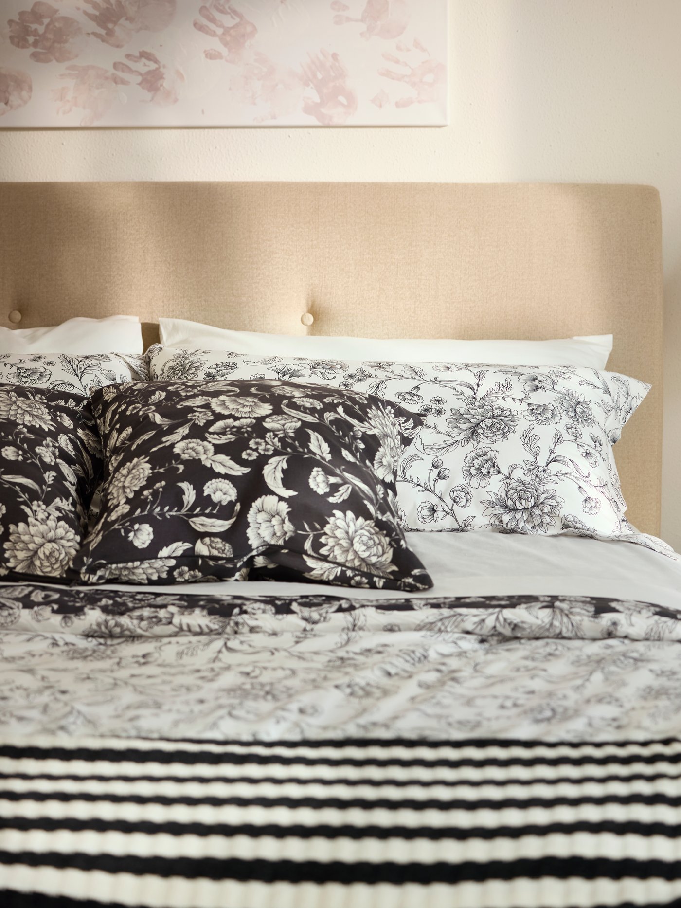 Close-up of bedding in beige, black and white with IDALINNEA comforter set and striped throw.