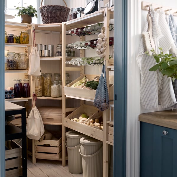 A kitchen pantry has several IVAR shelving units with food containers for storing food items placed on the shelves.