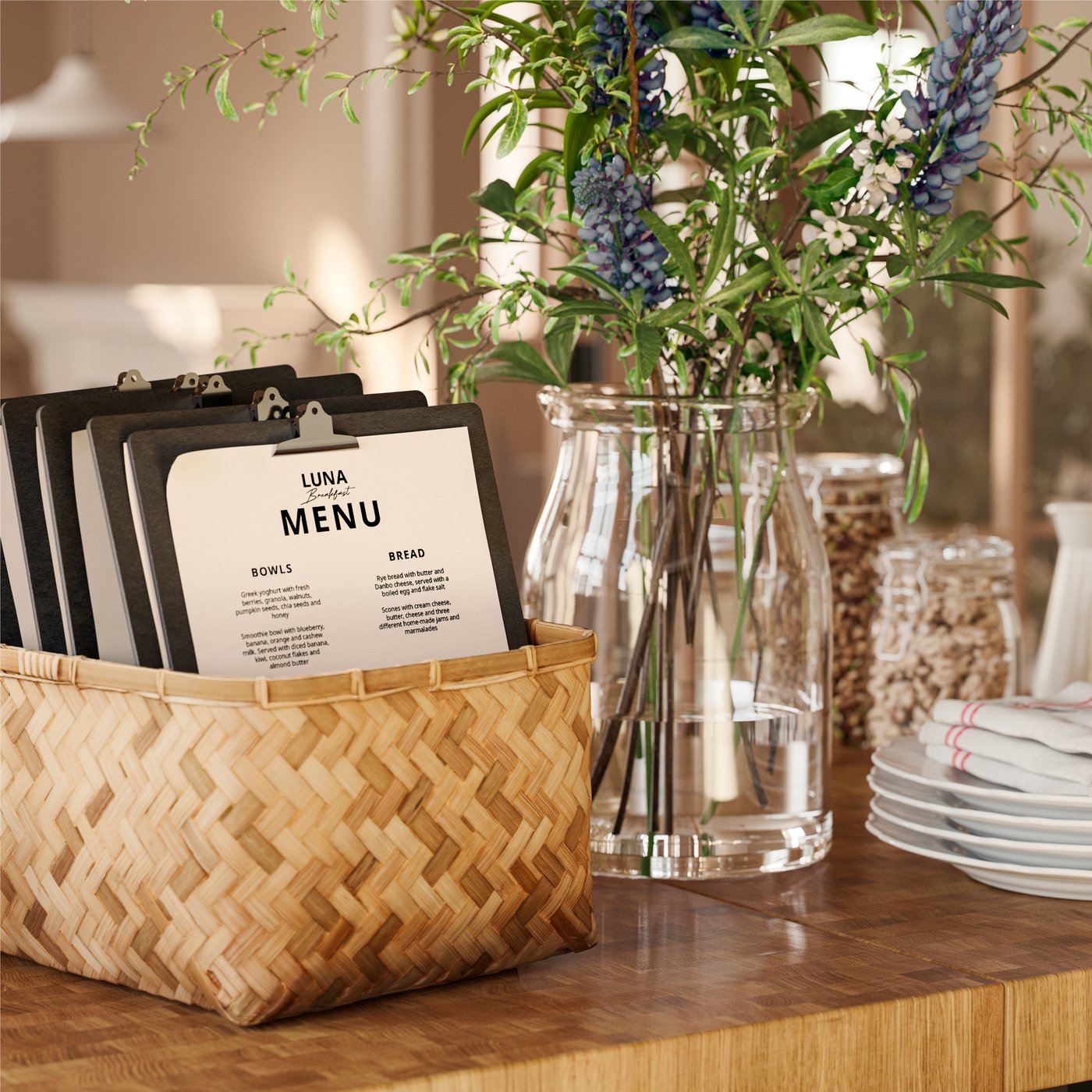Un cestino MJÖLKKANNA in bambù intrecciato contiene cartelle portadocumenti e menu su un tavolo accanto a un vaso di fiori e una pila di piatti.