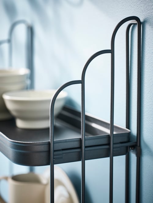 Bathroom close-up of a black APOTEKARE wall shelf made of steel, supporting a beige SANDSKÄDDA bowl.
