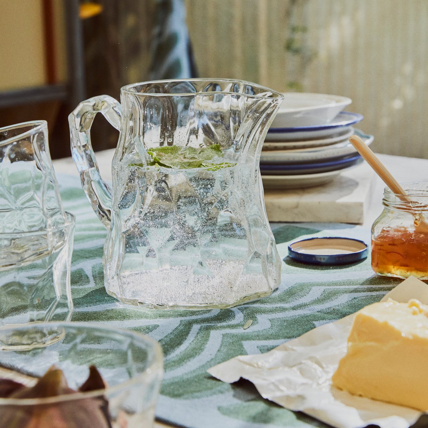 Four BASTUA glasses stand on a concrete surface with water splashes, with sunlight refracting in their irregular facets.