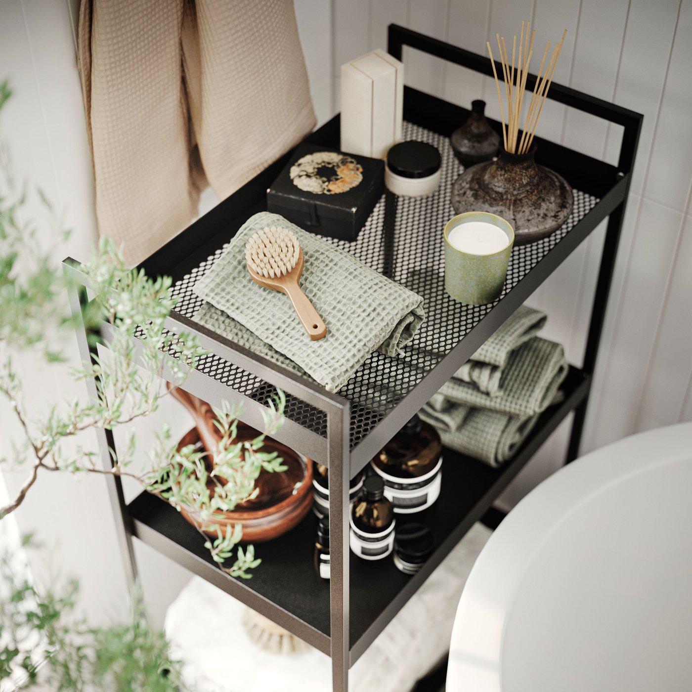 Une desserte NISSAFORS noire vue du dessus avec des flacons, des serviettes et des articles de toilette sur ses tablettes.