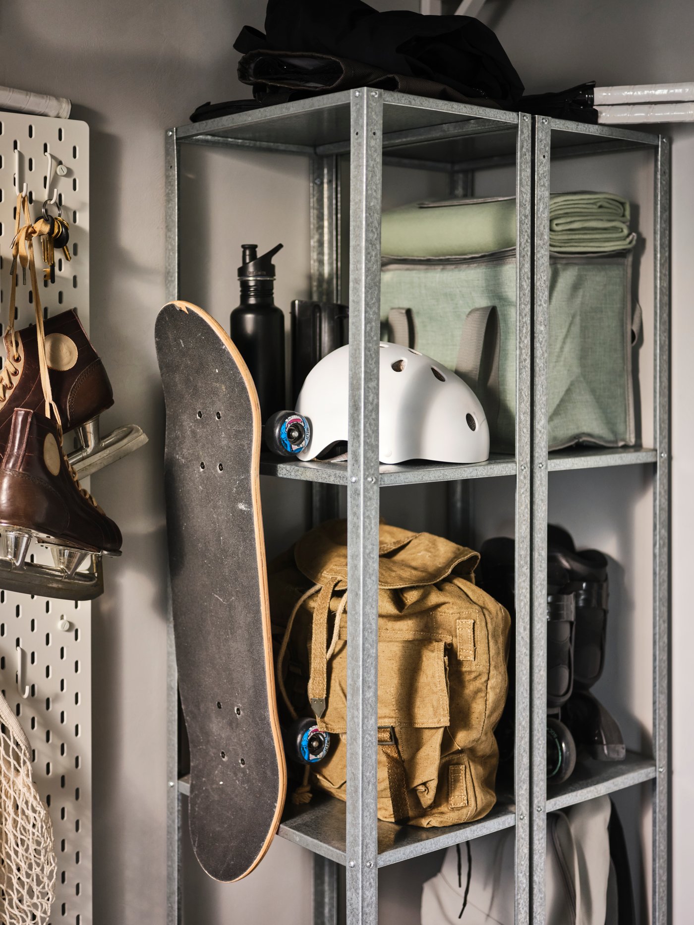 IKEA HYLLIS open shelving unit in the garage holding backpacks and a skate board. 