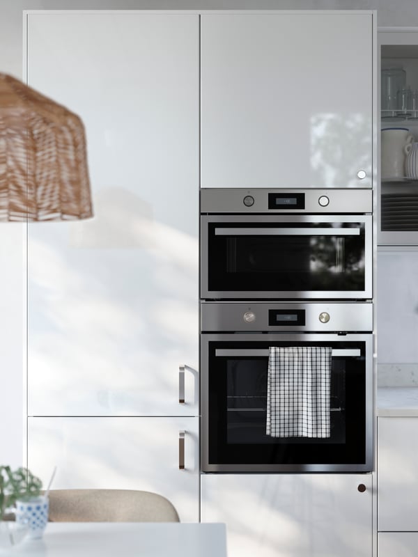 A kitchen has cabinets with glossy RINGHYLT fronts with an integrated fridge/freezer, a built-in oven and microwave oven.
