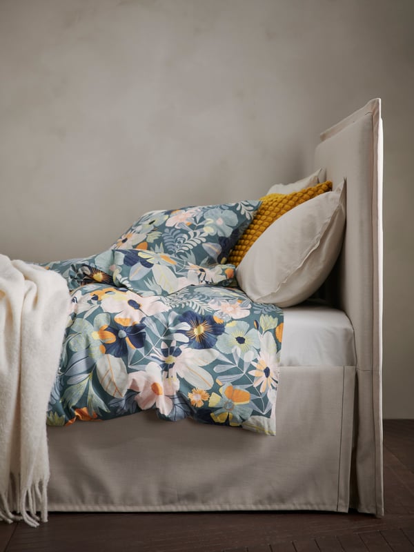 Close up of TÄRNKULLEN bed dressed with FÄLTGRÄSMOTT duvet cover and pillows and a white KLIPPOXEL throw.