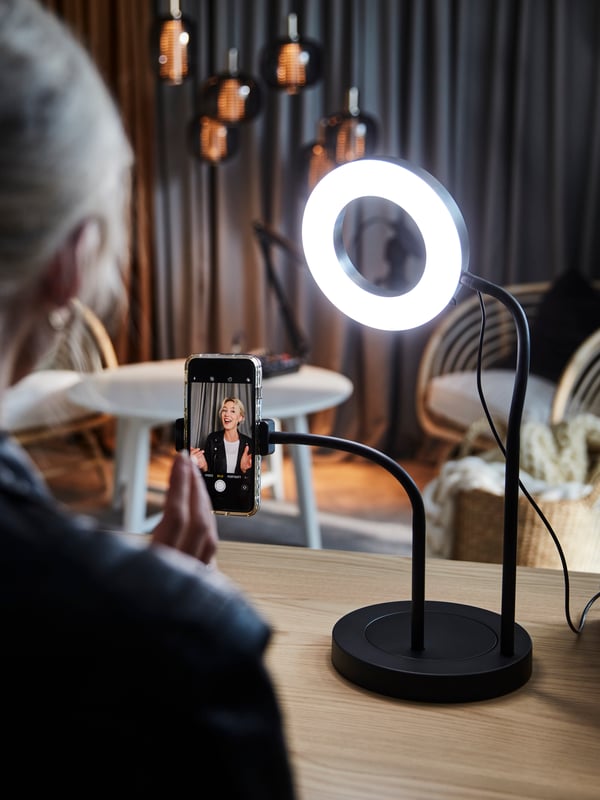 A woman is looking into a LÅNESPELARE ring light.