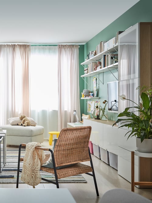 Living room with an armchair with throw, a TV bench, a footstool with storage, and a storage combination with glass doors.