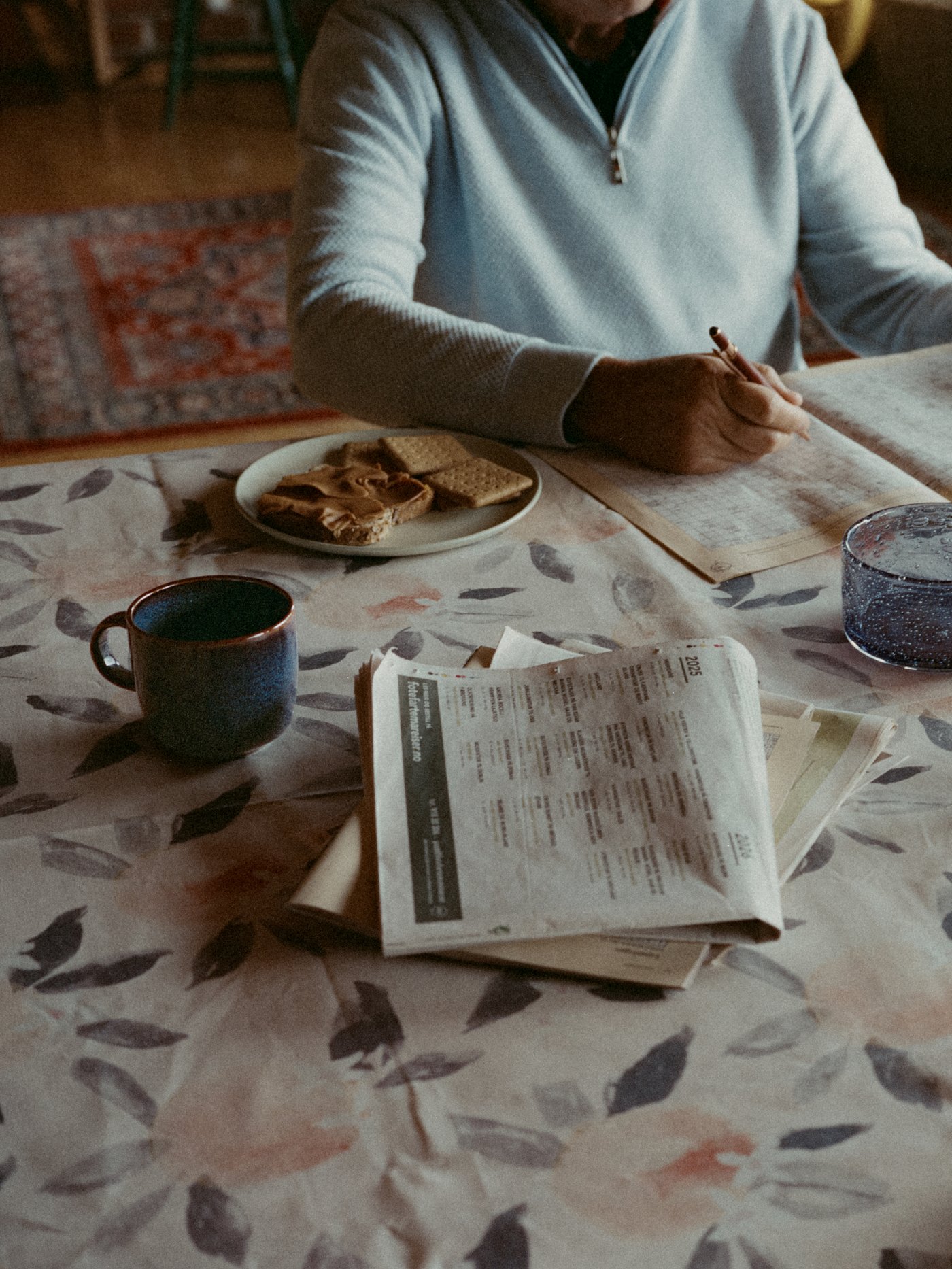 En person sitter med kryssord ved kjøkkenbordet.