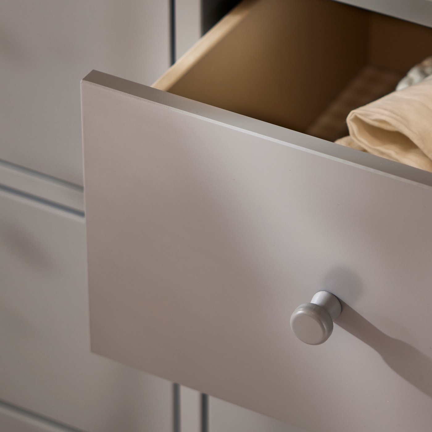 A partially opened drawer in the GULLABERG chest of drawers revealing folded textiles inside.