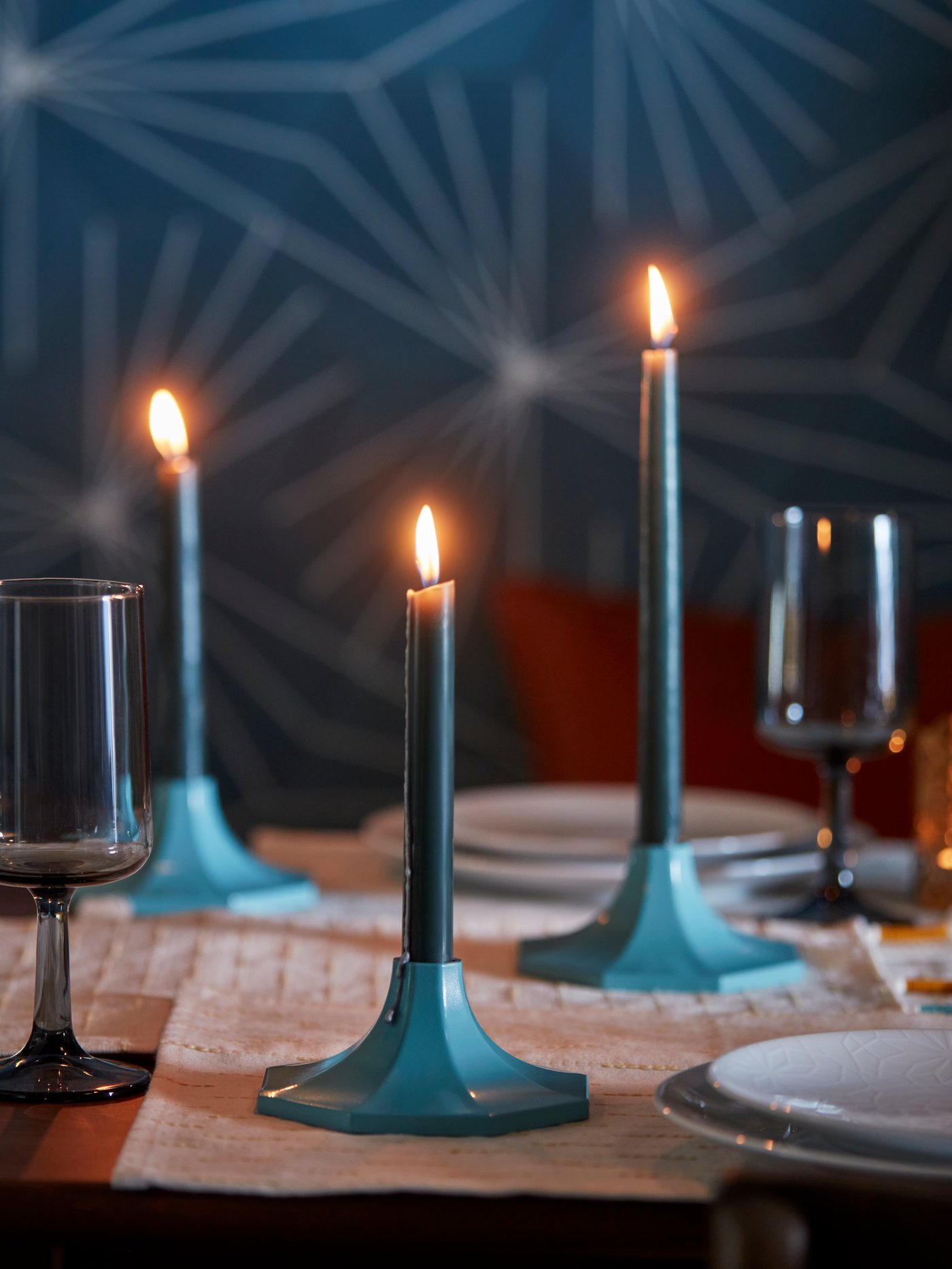 Espelmes en candelers turquesa enceses sobre una taula parada, creant un ambient càlid i acollidor.