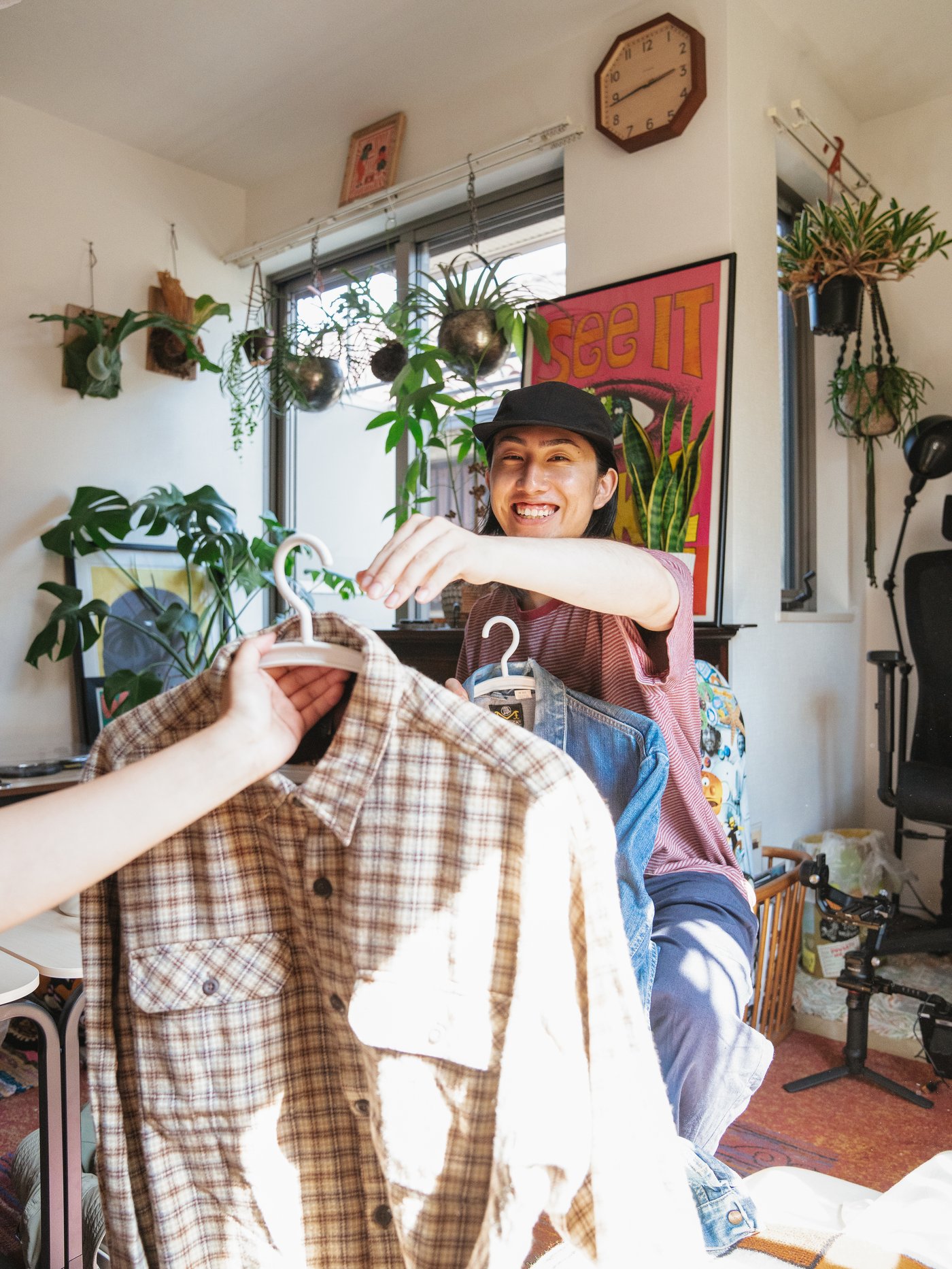 A person handing another person a hanger with a shirt on it.