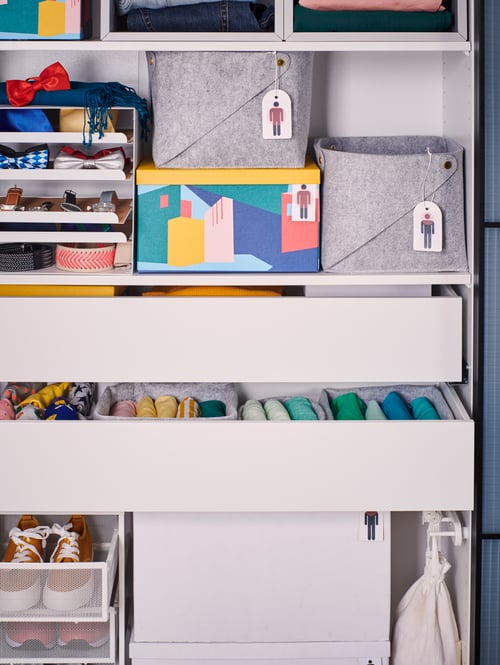 A PUDDA basket and a KVISSLE letter tray in a wardrobe frame that also contains various other drawers and boxes for storage.