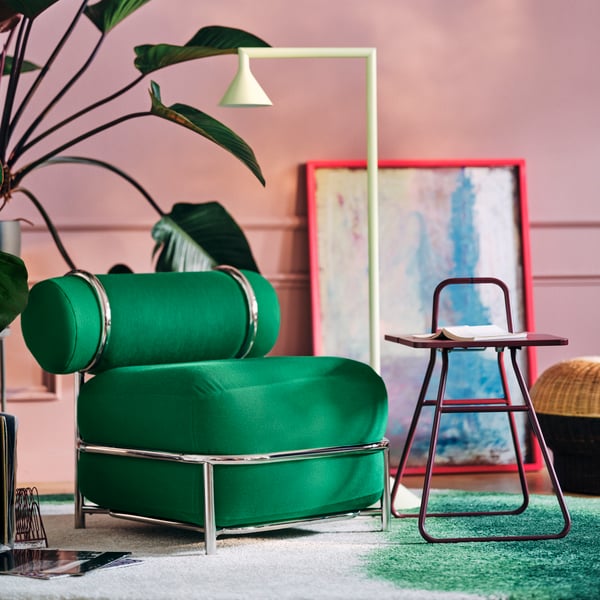 Contemporary lounge corner with a green IKEA PS 2026 easy chair, a dark red side table and framed artwork.