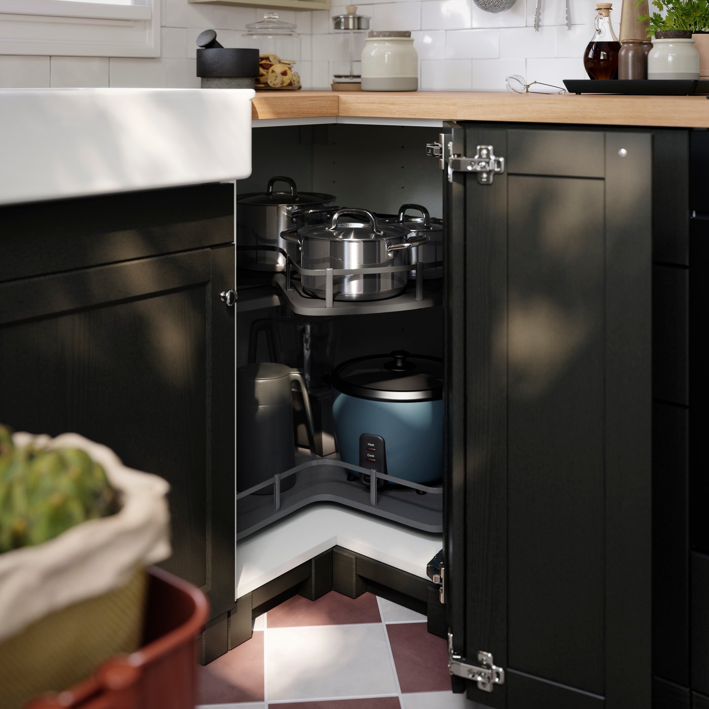A kitchen with a white METOD corner base cabinet and carousel, featuring pots and pans neatly arranged inside.