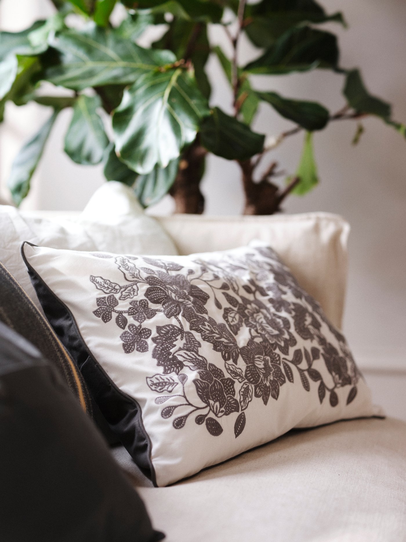 SKUGGNÄVA cushion cover with black floral print placed in a white sofa.