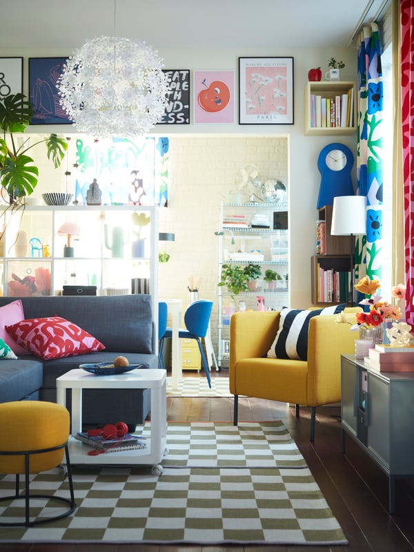 Ein lebendiges Wohnzimmer mit KLASSRUM-Teppichen, einem FRIHETEN-Schlafsofa, einem TINGBY-Beistelltisch, einem EKERÖ-Sessel und reichlich Dekoration.