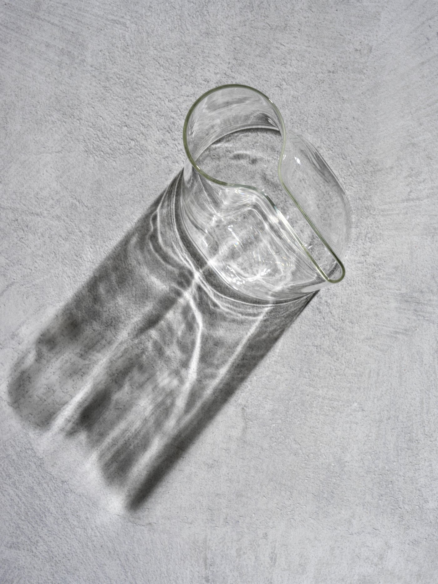 En CHILIFRUKT glasvas som också är en tillbringare ovanifrån på betonggolv.